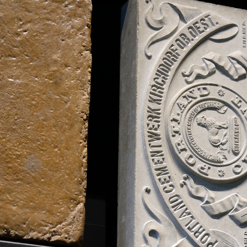 Two rectangular objects side by side; left a brownish stone slab with uneven surface, right a light-colored slab
                                 embossed with decorative lettering and ornaments. (AI-generated alt-text, generated with GPT-4.1-mini)