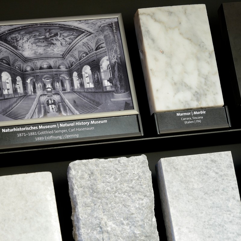 Black-and-white photo and mineral samples with labels in a display case (AI-generated alt-text, generated with GPT-4.1-mini)