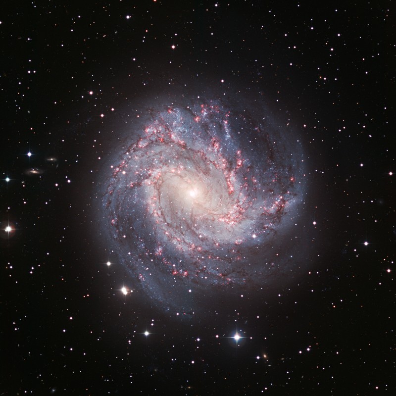 Spiralgalaxie Messier 83 mit hell leuchtendem Kern, Spiralarme mit bläulichem Nebel und rötlichen Sternentstehungsgebieten,
                                 umgeben von Sternen auf schwarzem Hintergrund. (KI-generierter Alt-Text, erstellt mit GPT-4.1-mini)