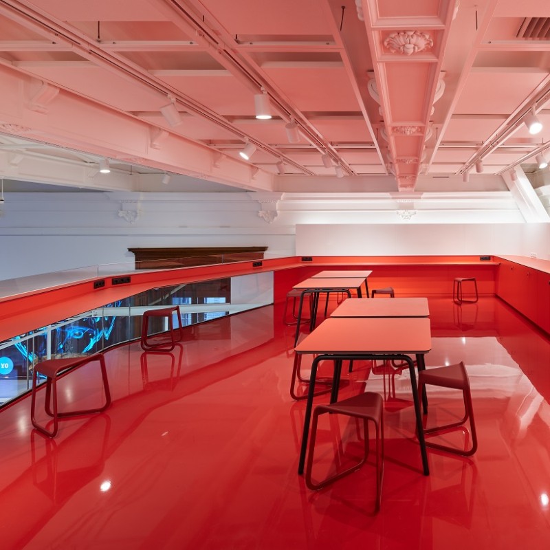 Red room with glossy floor, multiple tables and stools. Modern ceiling with exposed ventilation pipes. (AI-generated
                                 alt-text, generated with GPT-4.1-mini)