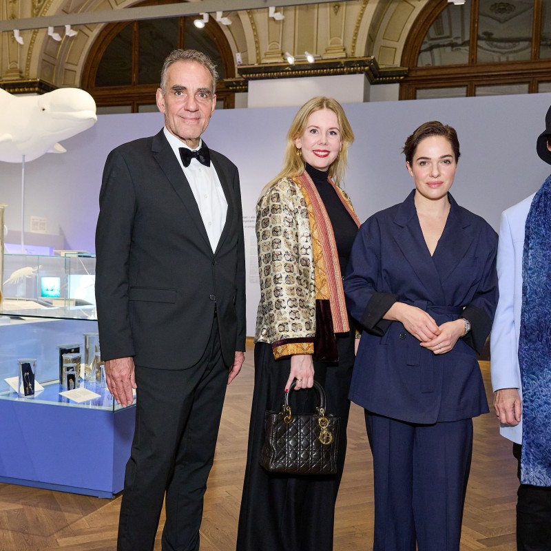 Two men and two women stand in a
                                 museum exhibition with a white whale sculpture and blue display cases. (AI-generated alt-text, generated with GPT-4.1-mini)