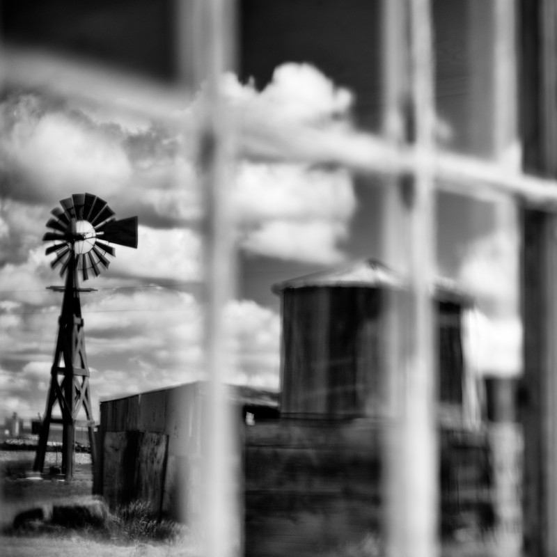 Black-and-white reflection of a windmill and several buildings in a window of a wooden wall. (AI-generated alt-text,
                                 generated with GPT-4.1-mini)