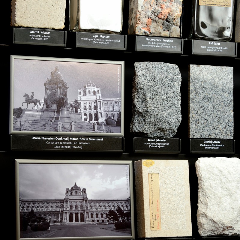 Display case with rock samples, two bottles, a historical photo of the Maria Theresa Monument, and a photo of the
                                 Museum of Art History. (AI-generated alt-text, generated with GPT-4.1-mini)