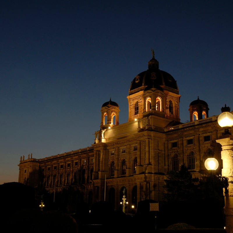 The illuminated Natural History Museum Vienna at dusk with several street lamps in the foreground. (AI-generated
                                 alt-text, generated with GPT-4.1-mini)