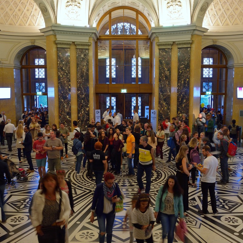 Large
                                 foyer with marble columns, ornate floor, and numerous people, some talking or walking. Tall vaulted ceiling in the background.
                                 (AI-generated alt-text, generated with GPT-4.1-mini)