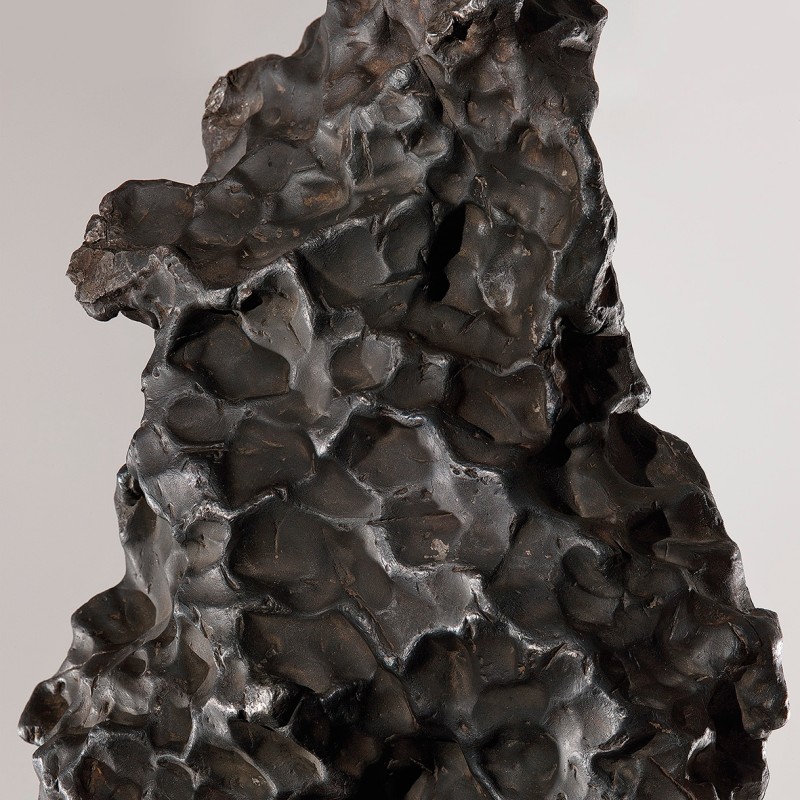 Dark, irregularly shaped iron meteorite
                                 with multiple round indentations on the surface. (AI-generated alt-text, generated with GPT-4.1-mini)