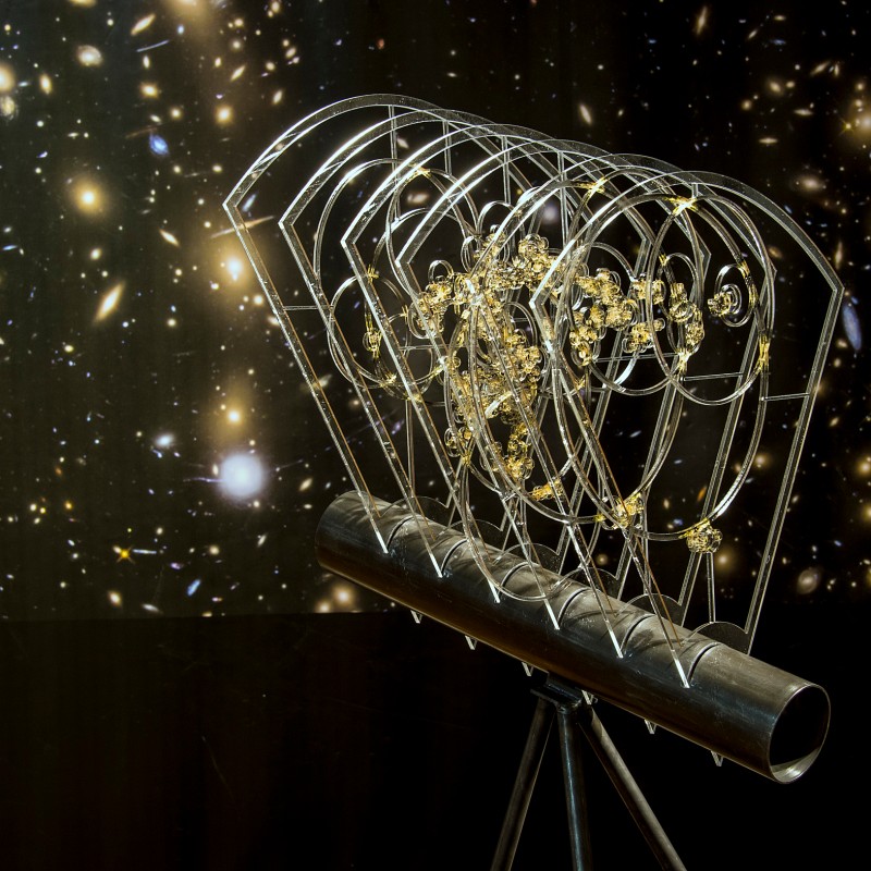 Three-dimensional
                                 model of the solar system with gold-colored details, made of wire and metal tube, set against a background with galaxies and
                                 stars. (AI-generated alt-text, generated with GPT-4.1-mini)