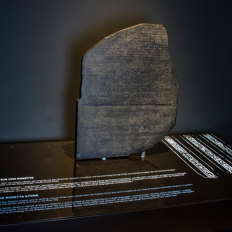 Der
                                 Stein von Rosetta in einer Vitrine, mit Text auf Deutsch und Englisch auf dem Sockel. (KI-generierter Alt-Text, erstellt mit
                                 GPT-4.1-mini)