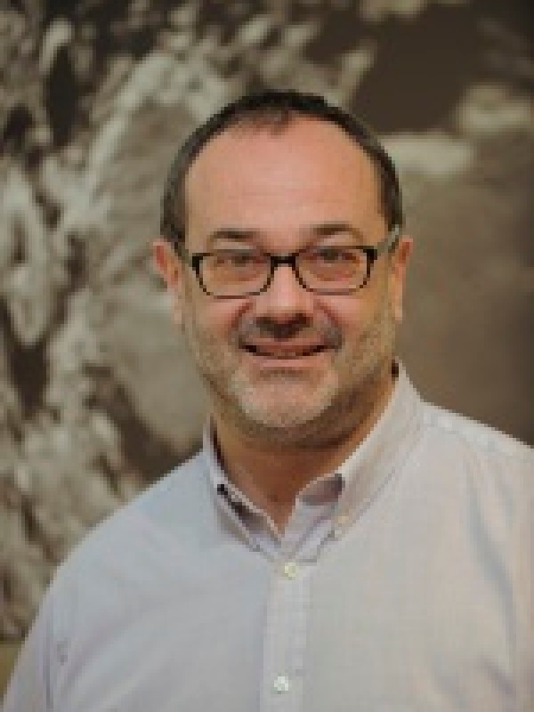 Mann mit Brille, kurzem Bart und grauem Hemd lächelt in die Kamera, unscharfer Hintergrund. (KI-generierter Alt-Text,
                                 erstellt mit GPT-4.1-mini)