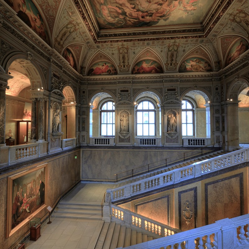 Large, ornate staircase with elaborately decorated ceiling paintings, tall windows, and marble railings. (AI-generated
                                 alt-text, generated with GPT-4.1-mini)