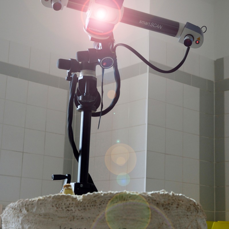 3D scanner with illuminated lens positioned on a stone base with engraved text. (AI-generated alt-text, generated
                                 with GPT-4.1-mini)