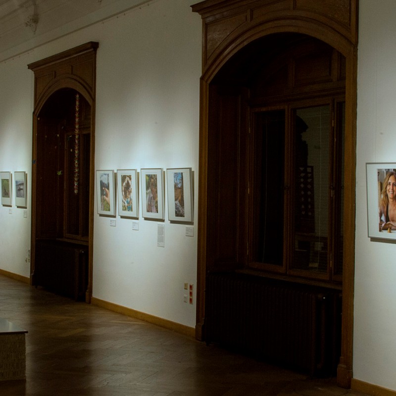 Gallery wall with framed portrait photographs, on the left a large portrait of a girl with a peace sign made of
                                 flowers. (AI-generated alt-text, generated with GPT-4.1-mini)