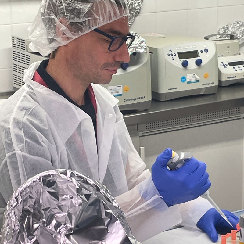 Mann mit Schutzkleidung in einem Labor beim Pipettieren