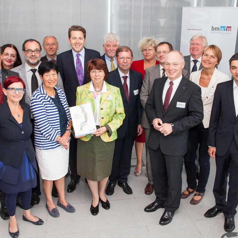 Group of thirteen adults standing in a bright room, some smiling, one woman holding a folder with a colorful cover.
                                 (AI-generated alt-text, generated with GPT-4.1-mini)