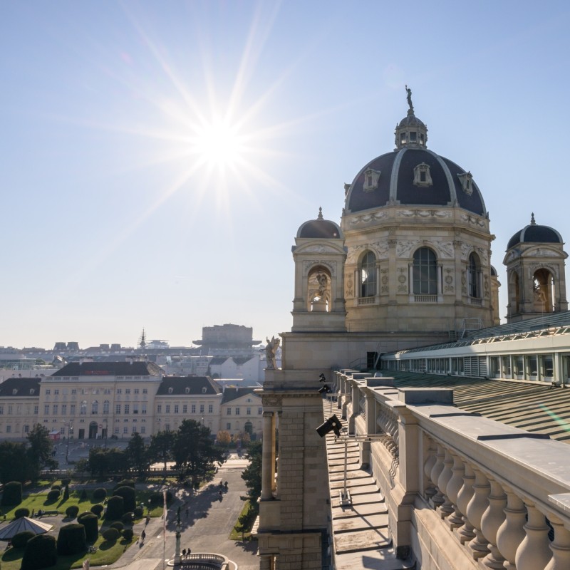 : Dach des Naturhistorischen Museums Wien bei Sonnenschein, Kuppel und Fassade mit Blick auf den Platz und die umliegenden Gebäude. (KI-generierter Alt-Text, erstellt mit GPT-4.1-mini)