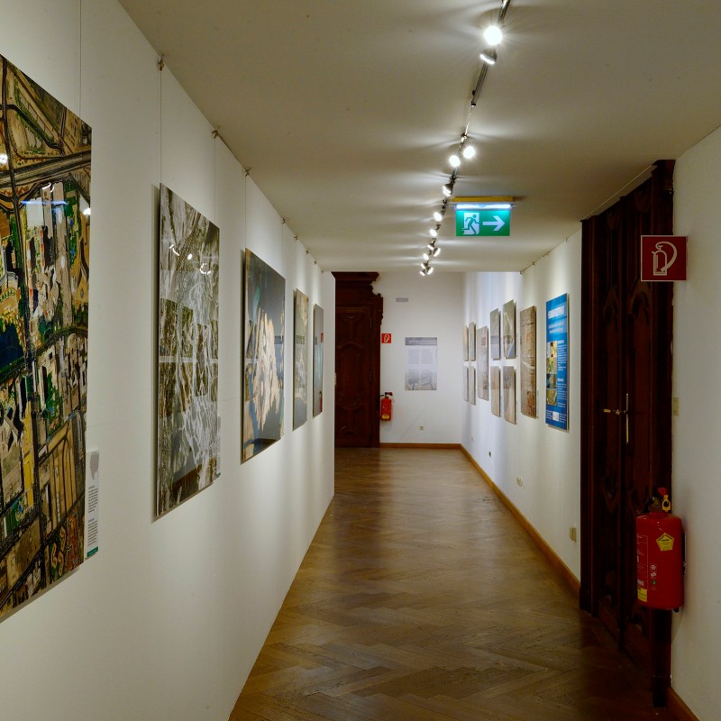 Long museum corridor with large wall panels and photographs for the 'Human Footprint' exhibition, wood floor and
                                 bright ceiling lights. (AI-generated alt-text, generated with GPT-4.1-mini)