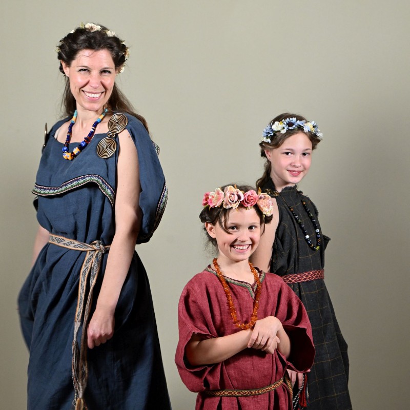 A woman and two girls are wearing historical clothing