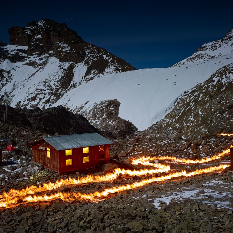 Wooden hut in a rocky mountain landscape in front of a glacier, with a glowing light trail on the ground. (AI-generated
                                 alt-text, generated with GPT-4.1-mini)